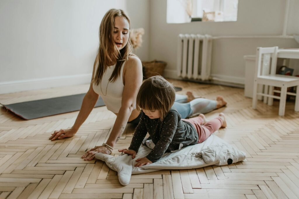 A woman in her daughter in their brightly lit room lying on a comfortable floor performing yoga stretches to alleviate back pain