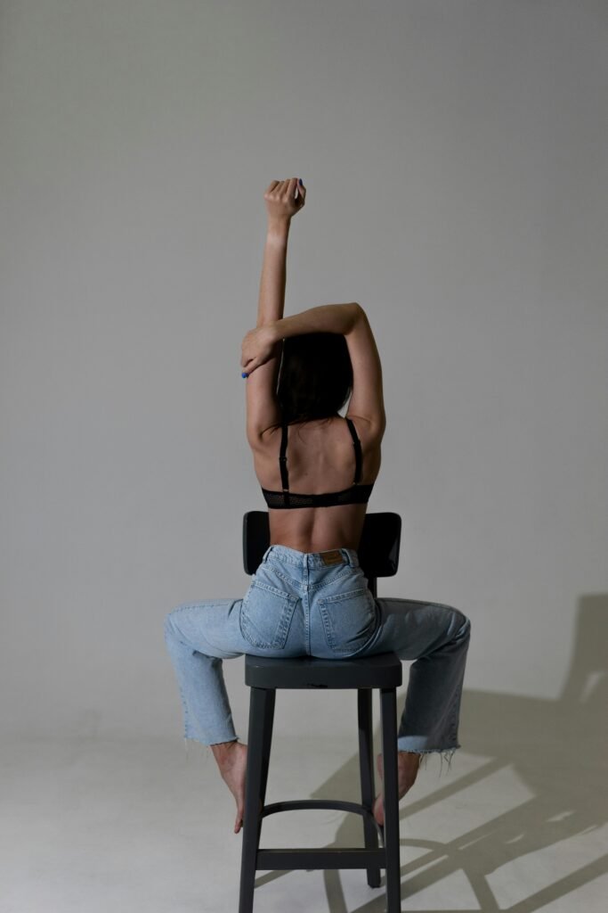 chair yoga sequence A woman in a cool dark room sitting backwards on a chair doing yoga poses and stretching comfortably