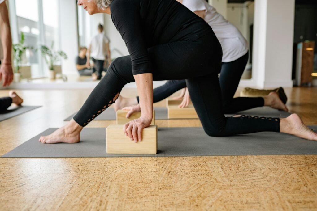 senior group class doing gentle yoga for balance improvement while using mats and yoga blocks