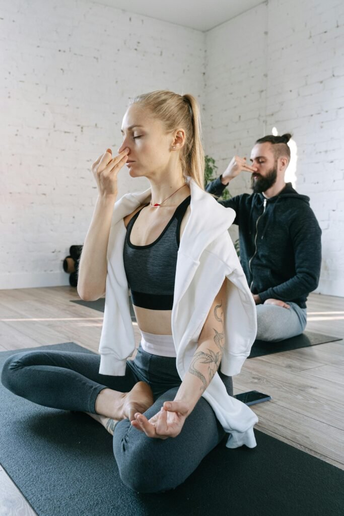Two people in a group restorative yoga class practicing alternate nostril breathing