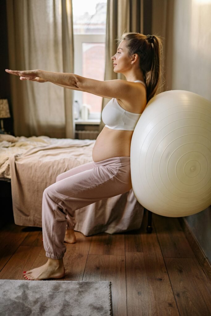 Pregnant woman with sciatica in her tranquil home doing a yoga pose while using a yoga ball as a prop against the wall