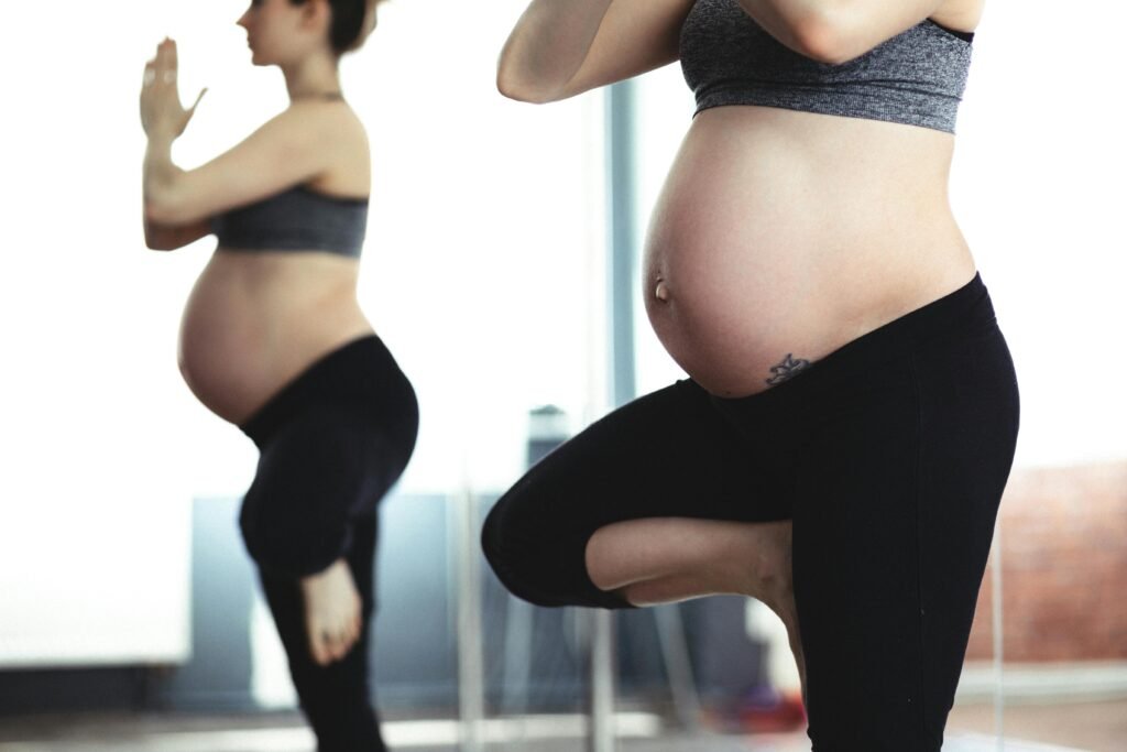 pregnant yoga practice woman during pregnancy standing up doing yoga with hands together in front of chest
