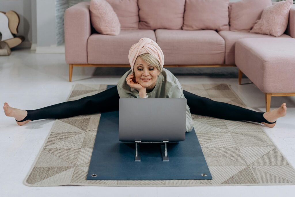 Older woman sitting in the comfort of her home on a yoga mat and rug while learning about yoga for pain relief