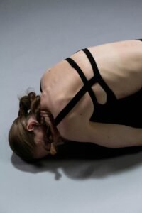 Young woman lying on the floor performing a deep stretch and doing yoga for back pain