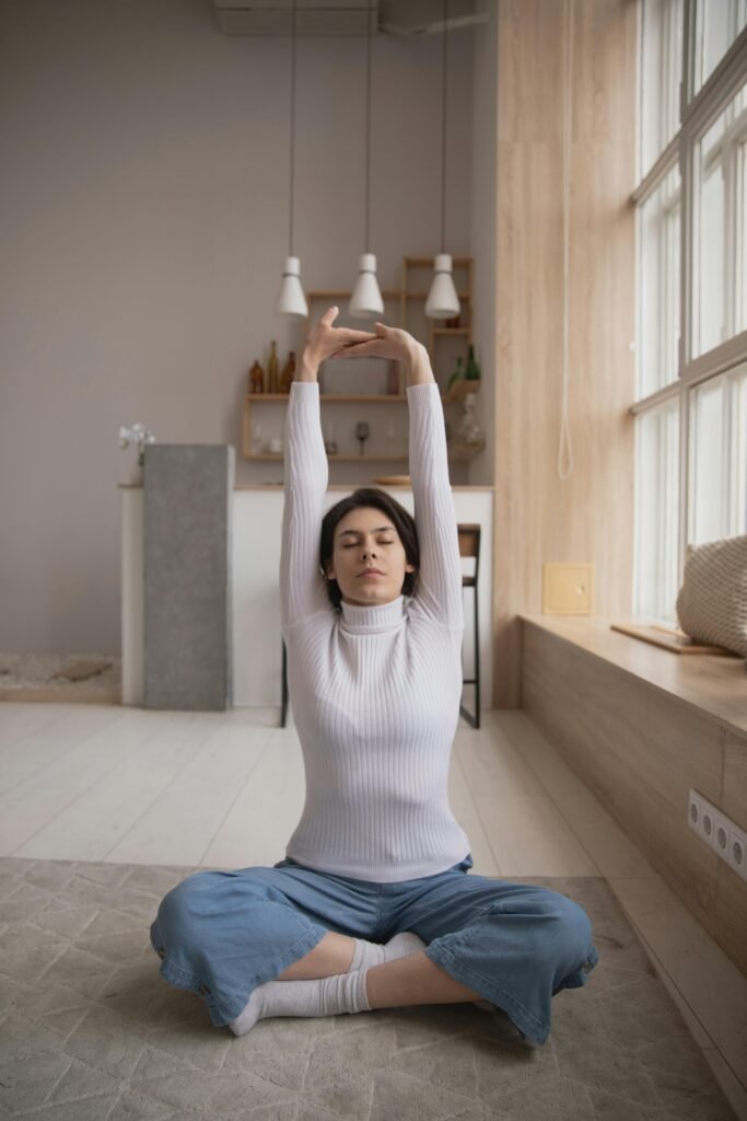 Young woman indoors in a comfortable and soothing environment. Sitting on a soft rug, she is performing a gentle yoga pose for migraine relief