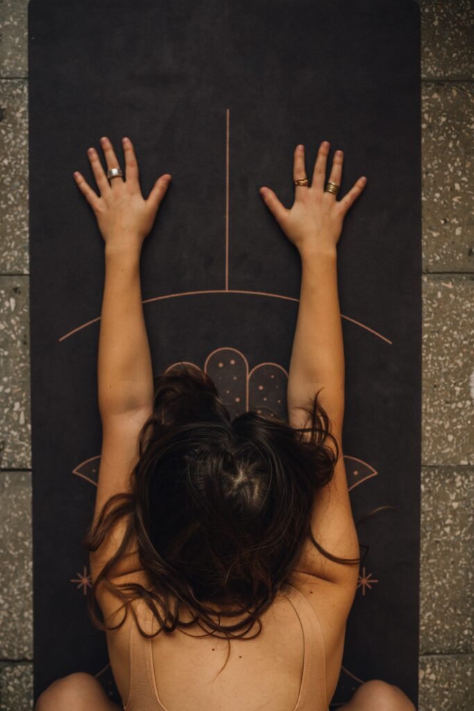 yoga pose for pelvic pain Woman lying forward on a black yoga mat in a specifically targeting a yoga for pelvic floor pain pose