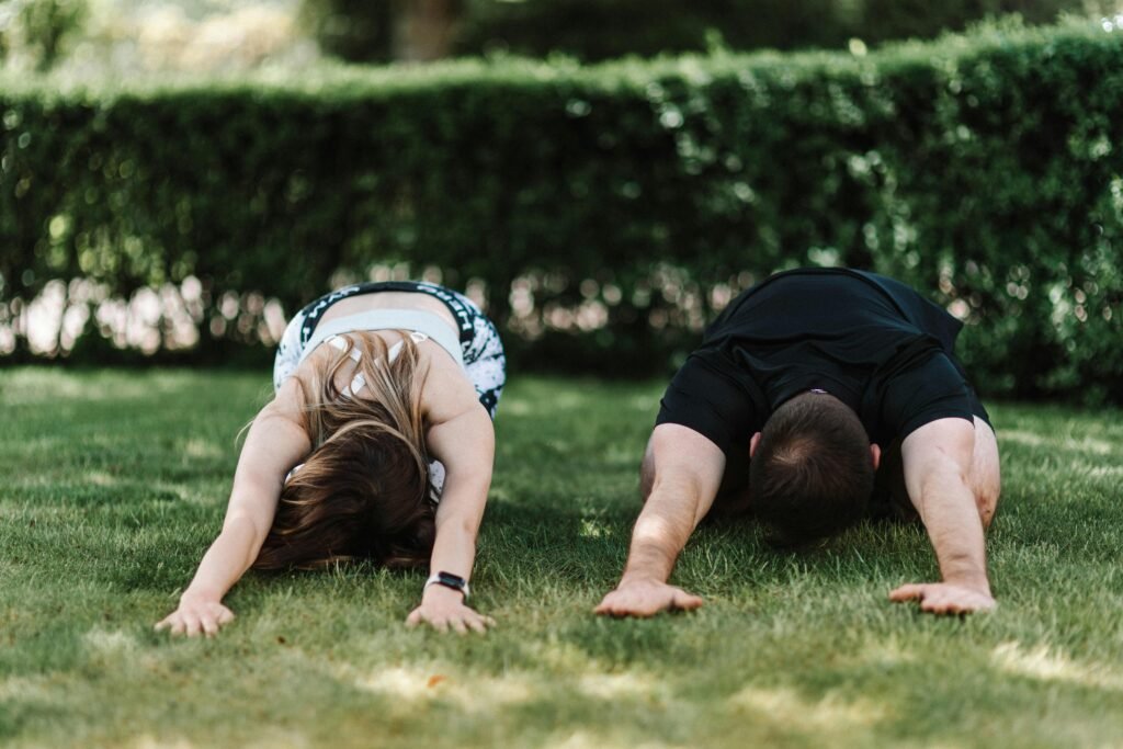 Group yoga class practicing child's pose outdoors on the grass for lower back pain relief