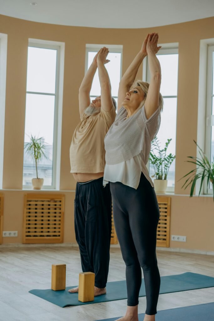 Two seniors balancing gently on yoga mats with yoga blocks placed on top
